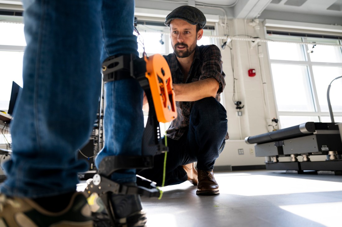 Max Shepherd adjusting an exoskeleton on the outside of Divyansh Gupta's leg. 