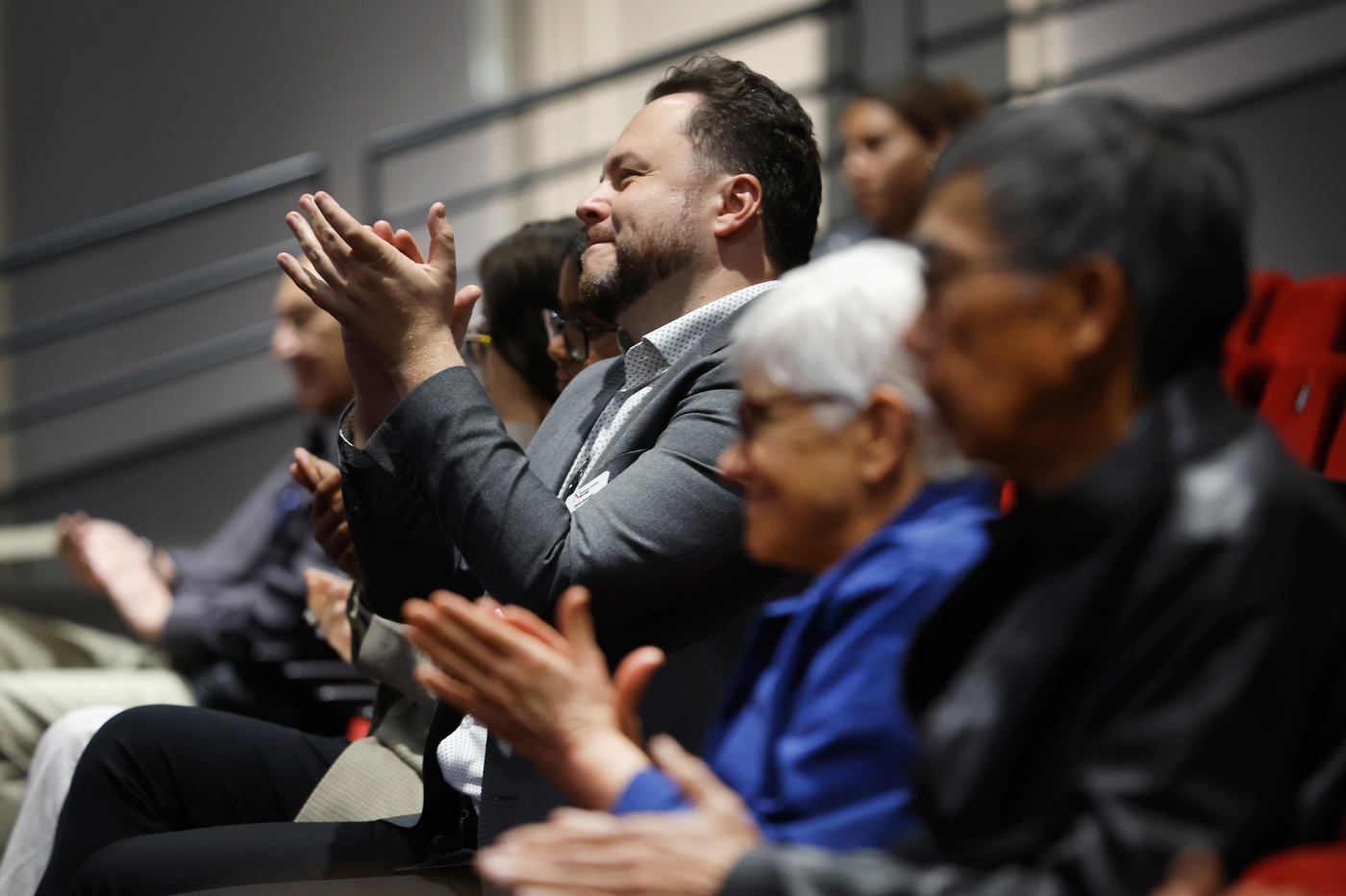 Audience members clapping for Dr. Rita Ng in an Oakland lecture hall. 