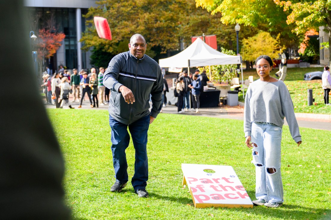 A student and their family play cornhole together. 