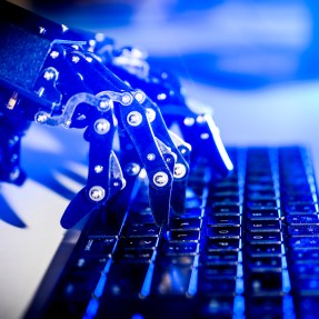 Robot hands typing on a keyboard.