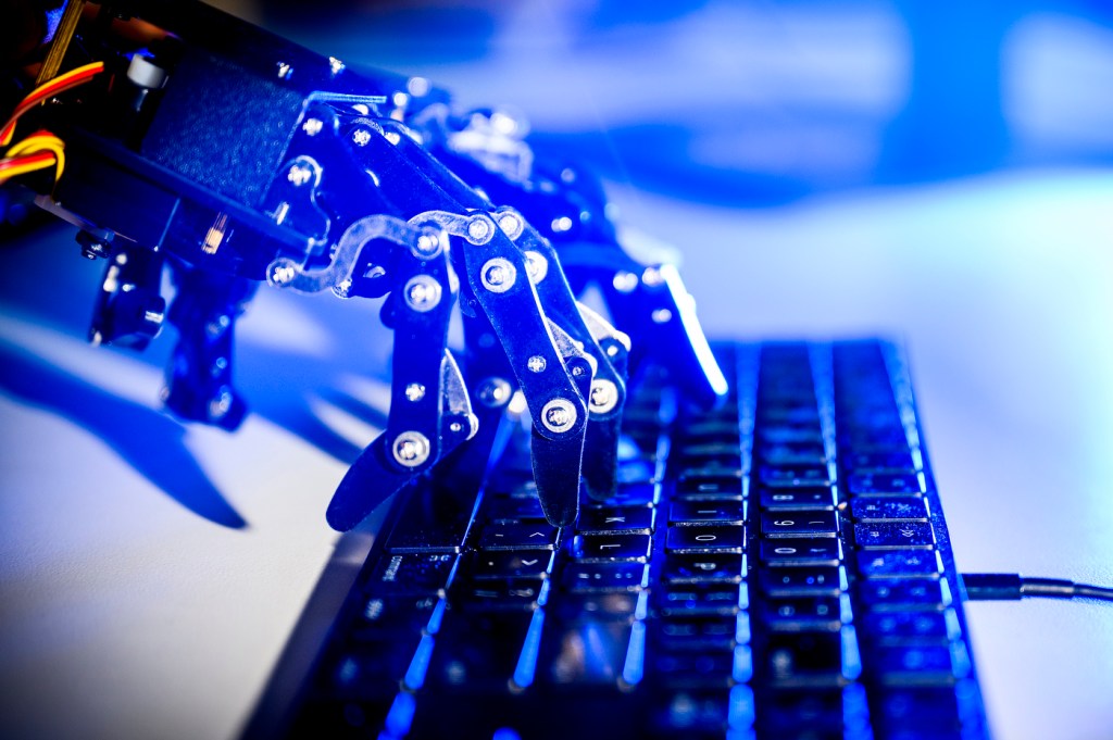 Robot hands typing on a keyboard.