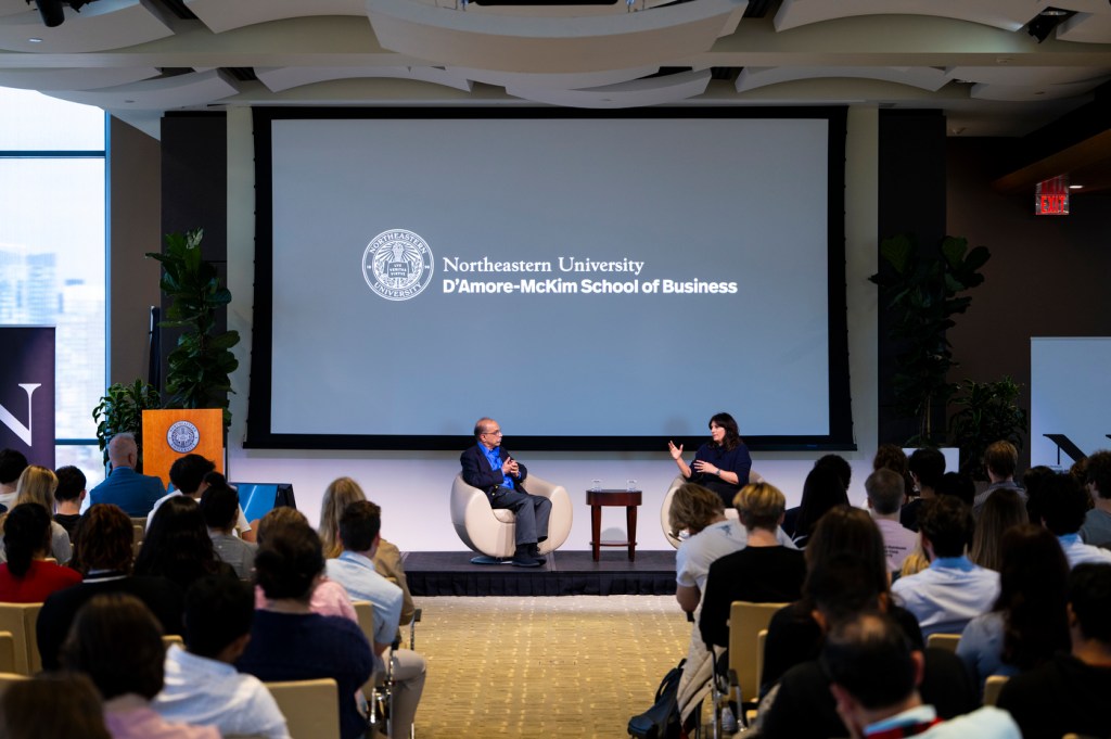 Speakers sitting on stage in front of an audience for a fireside chat.