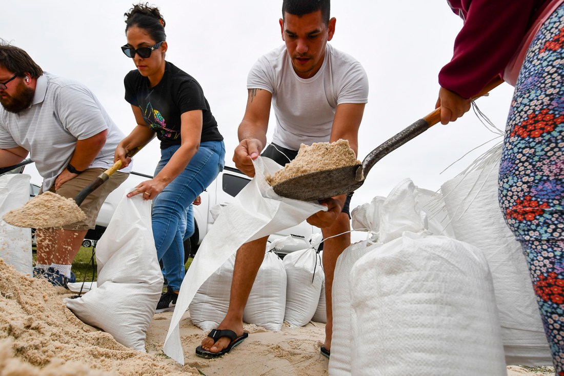 People on a beach collect sandbags.