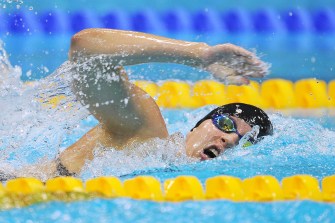 A swimmer competes in a swimming pool, wearing goggles and a swim cap.