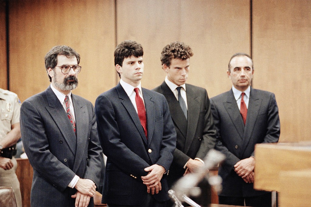 The Menendez brothers and their attorneys standing in court wearing suits and ties.