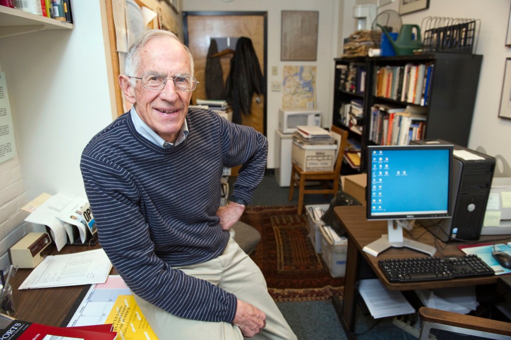 Nicholas Daniloff sitting on his desk smiling.