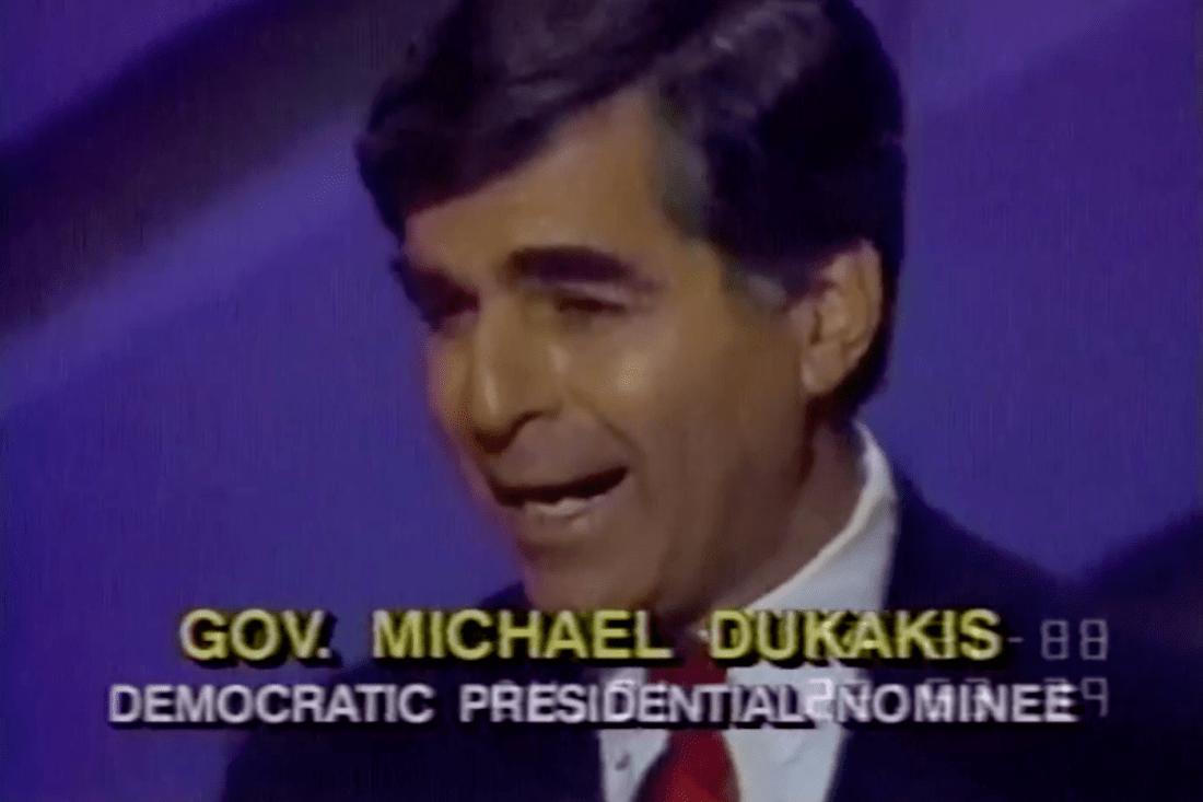 A screen shot of Michael Dukakis on TV with the caption 'GOV. MICHAEL DUKAKIS DEMOCRATIC PRESIDENTIAL NOMINEE'.