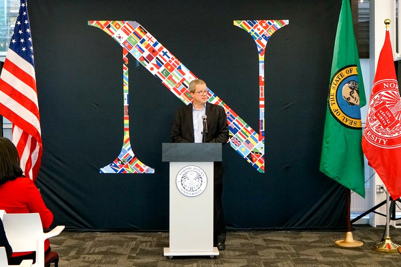 Dave Thurman speaking at a podium in front of the Northeastern logo.