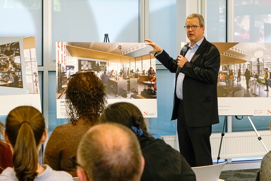 Dave Thurman gesturing to a poster of an architectural rendering displayed on an easel. 