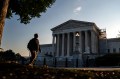 A person wearing a backpack walks past the U.S. Supreme Court.