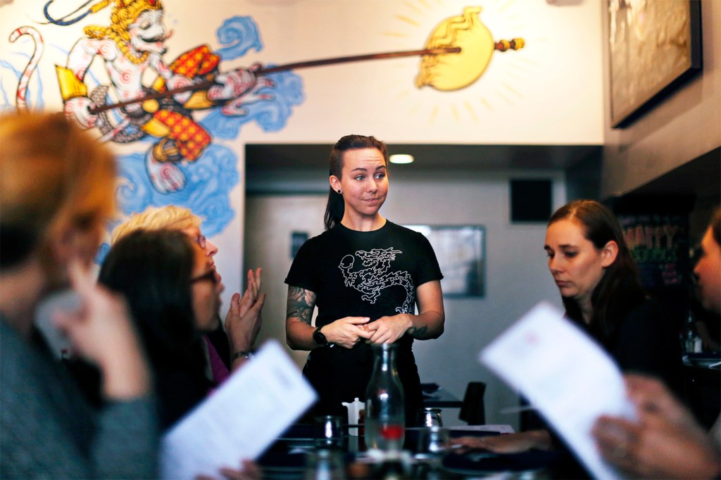 A server at a restaurant standing in front of a table of people holding menus.