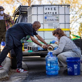 Volunteers filling up large blue bottles of drinking water.