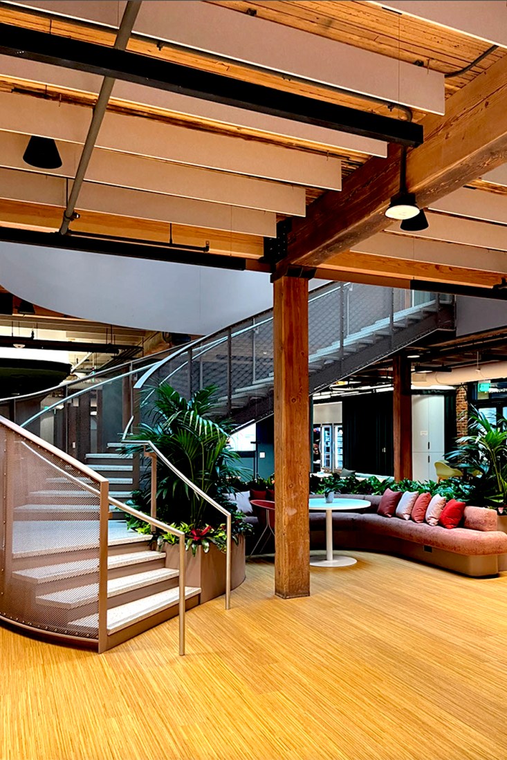 A curved staircase in the Seattle hub with an orange couch at the base.