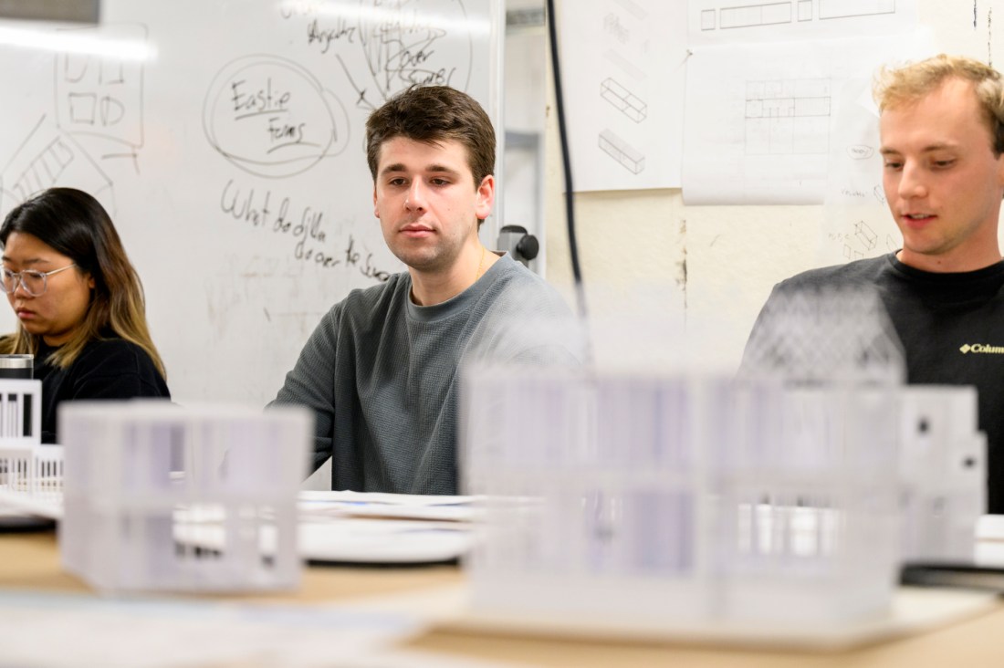 Three students sitting side by side in a graduate architecture capstone.