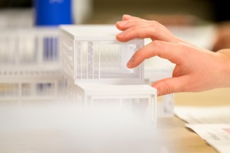 A persons hand reaching out for an architectural model.