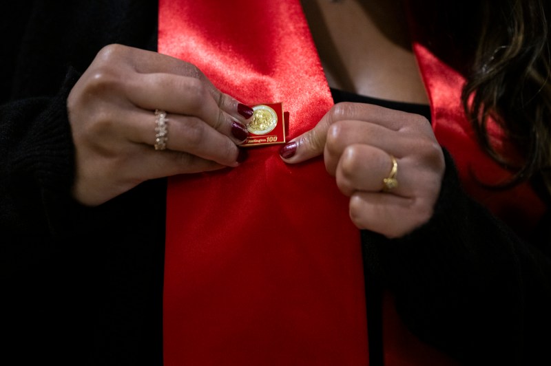 A Huntington 100 inductee attaching a red pin to a red sash.