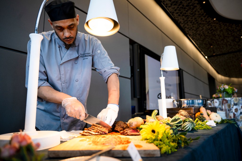 A chef prepares and slices meat at a decorative food station during an event.