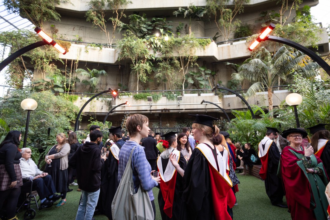 A group of people walking around an indoor greenhouse.