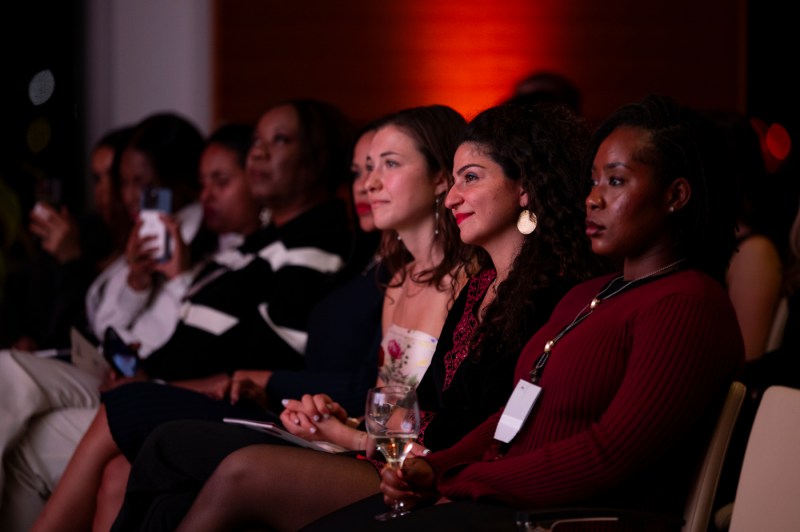 Audience members sitting in chairs listening to a speaker. 