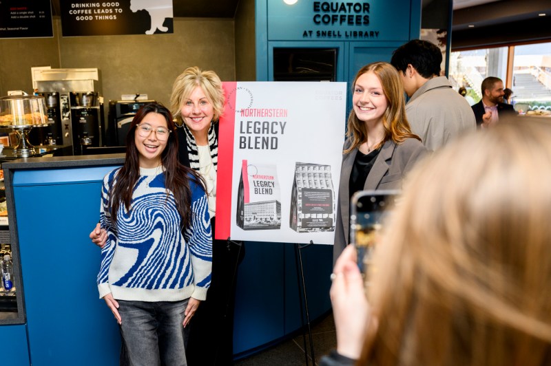 Helen Russell poses with two other people in front of a sign for the Northeastern Legacy Blend coffee.