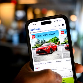 A hand holding an iPhone displaying a Facebook ad.
