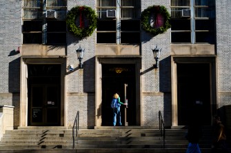 An individual enters a building adorned with seasonal decorations.