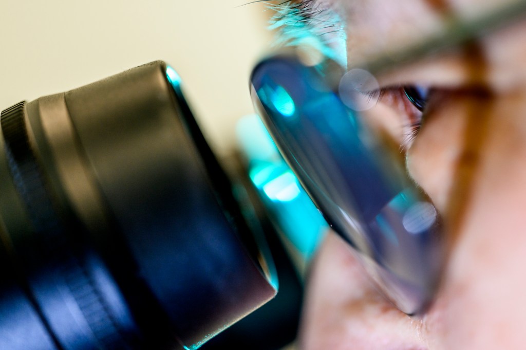 Ning Wang looking through a microscope.