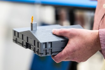 A person holding a 3D model of a church architectural redesign.