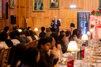 Joseph E. Aoun, President of Northeastern University, stands at a podium addressing students during a Thanksgiving dinner in Belfast.