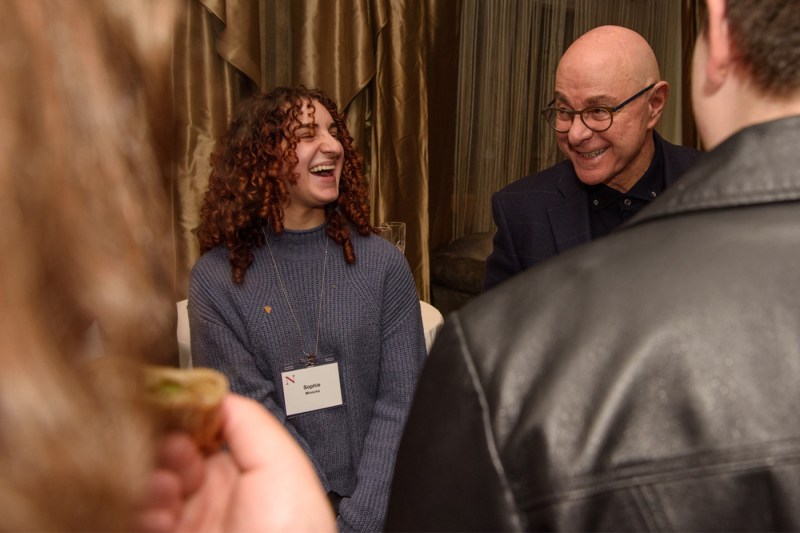 Joseph E. Aoun, Northeastern President, smiling and chatting with a student during Thanksgiving dinner.