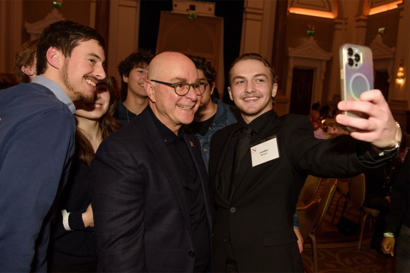 Joseph E. Aoun taking a selfie with a group of smiling students at the Thanksgiving dinner.