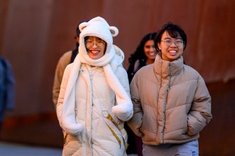 Students walk together on a university campus during a chilly day.