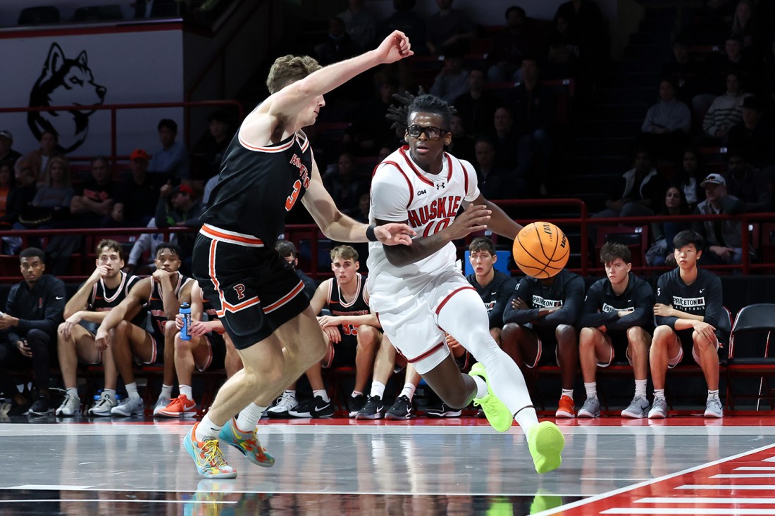 Harold Woods of Northeastern drives past a Princeton defender during a basketball game.