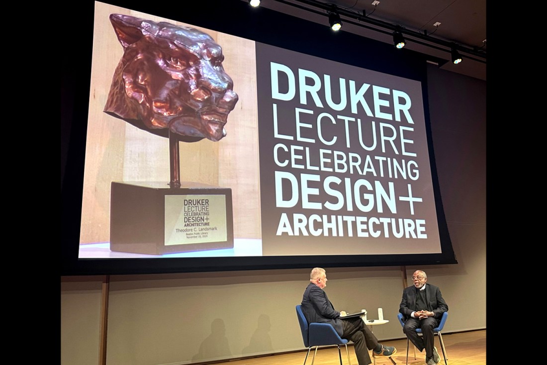 Ted Landsmark sitting on stage with another person in front of a slide that says 'Druker lecture celebrating Design+ architecture'.