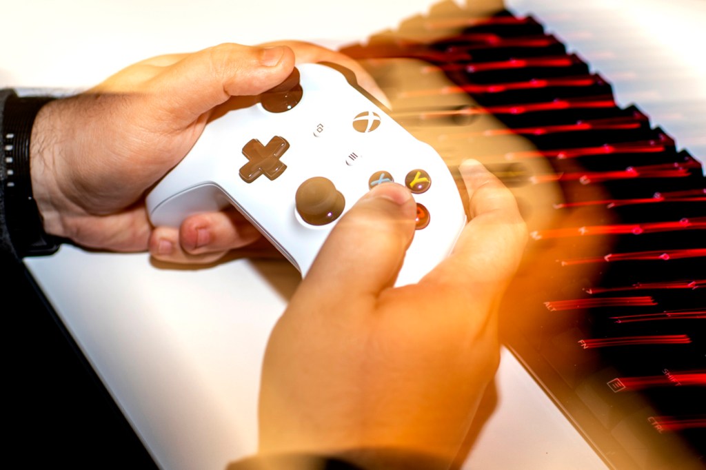 A person holding a white X-box controller in their hands.