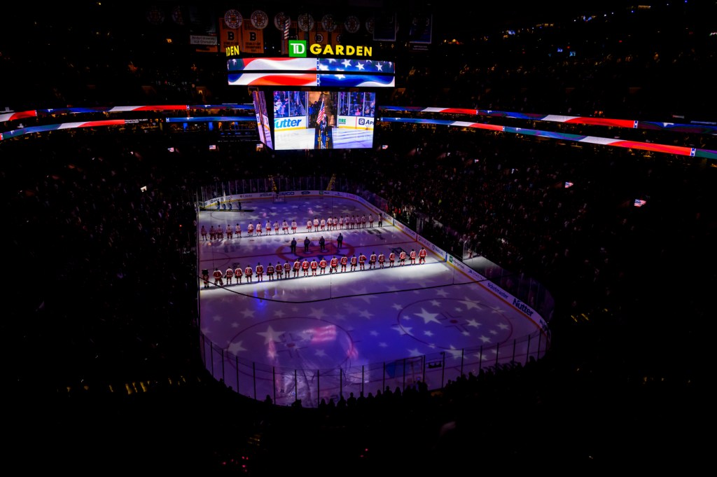 Hockey players stand in two rows on the ice in Boston's TD Garden before a game starts.