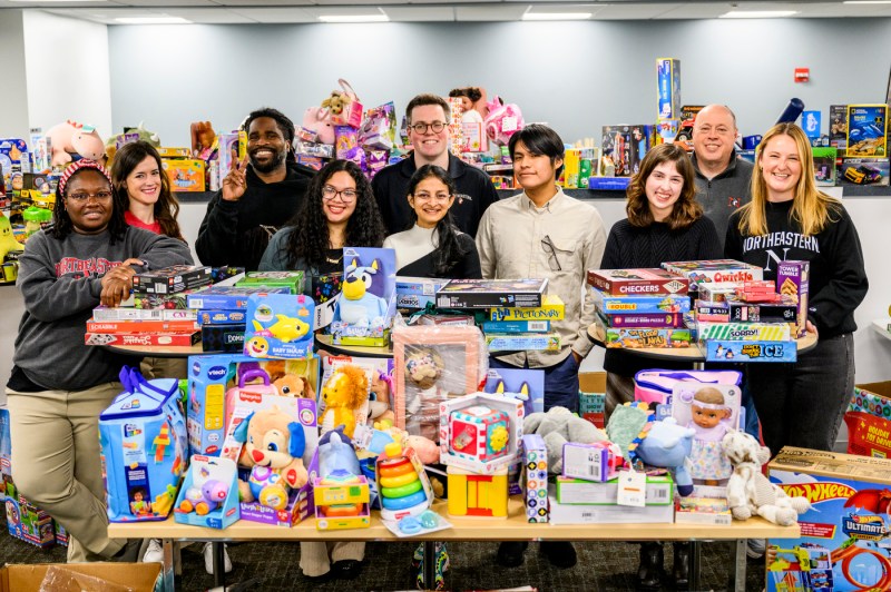 Northeastern staff members posing with a large stack of toys.