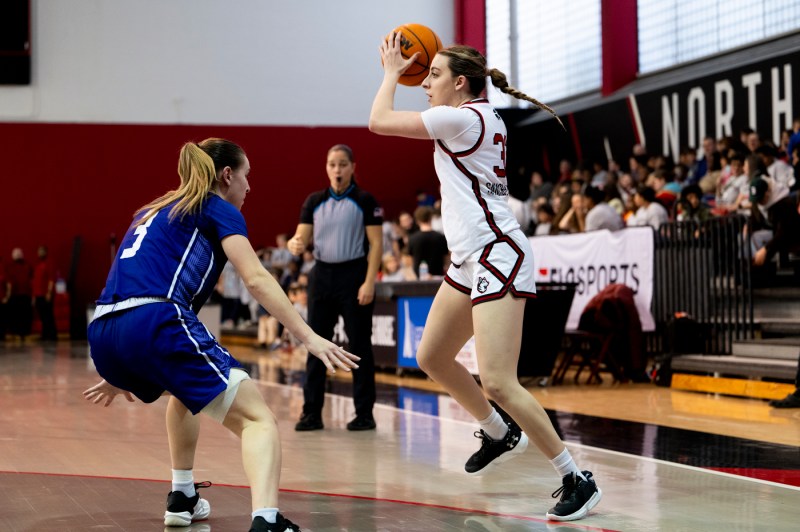 A women's basketball player holding the ball in the air.