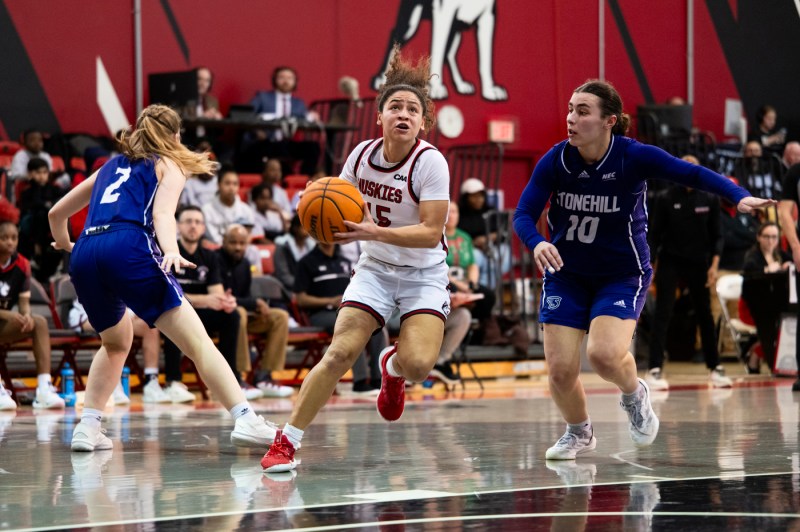 A woman's basketball player dribbling up to the net.