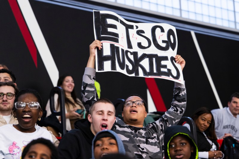 A student holding a sign that says 'Let's Go Huskies' on it.