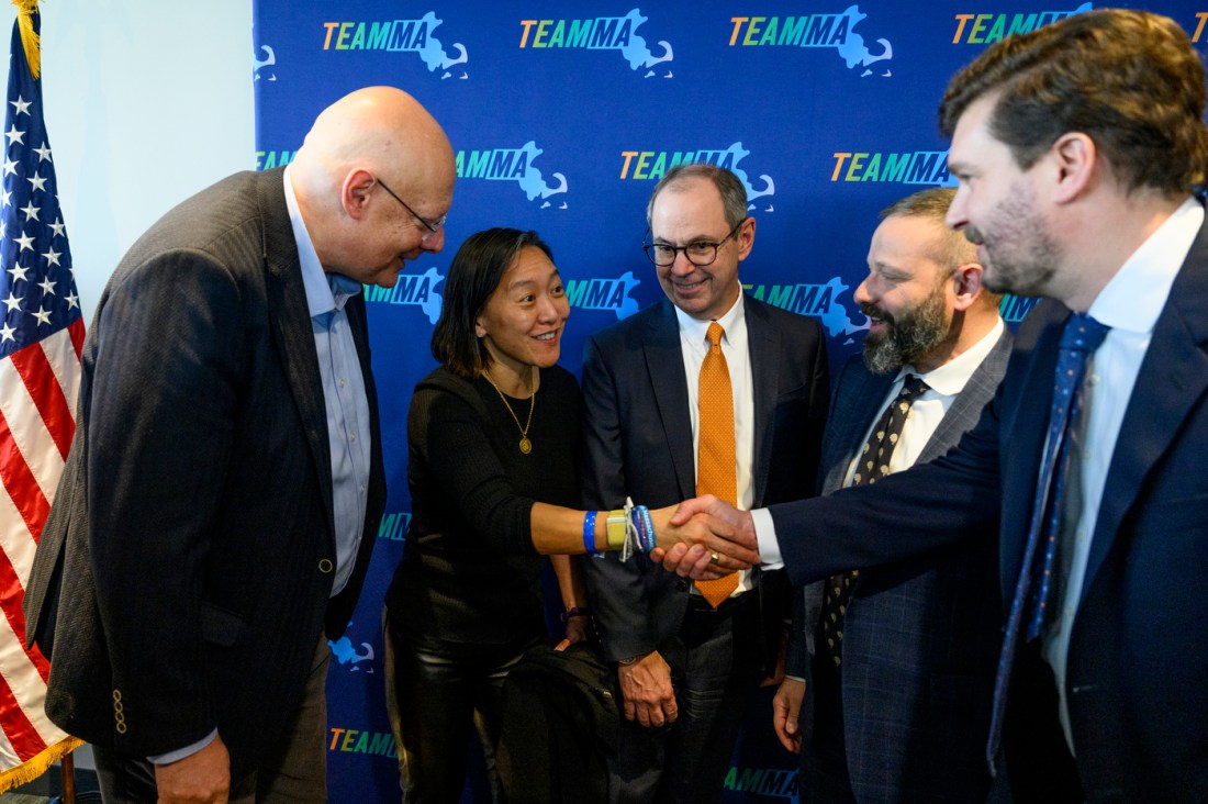 Five people talking and shaking hands at Maura Healey's AI announcement.