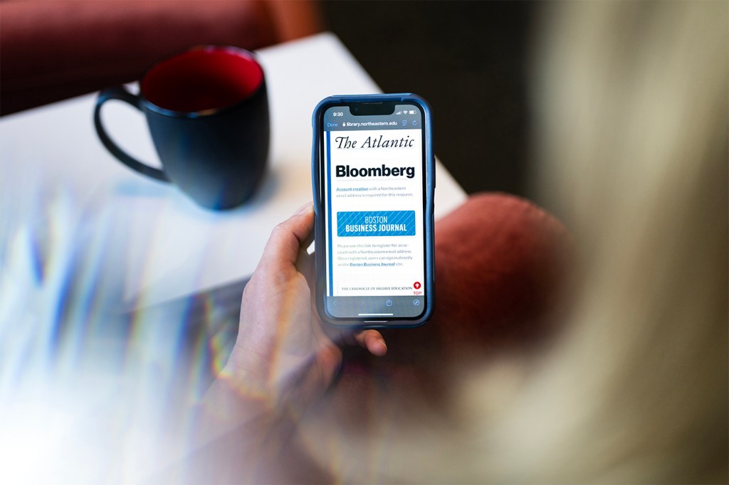 A person holding an iPhone open to a Bloomberg subscription redemption screen.