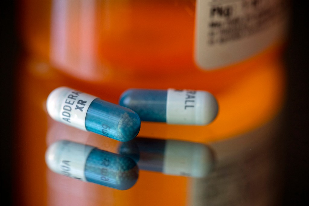 Adderall capsules on a glass surface.