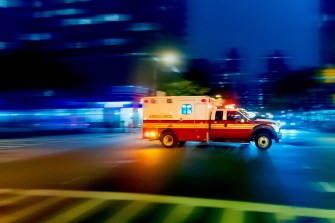 A time lapse photo of an ambulance speeding across an intersection.