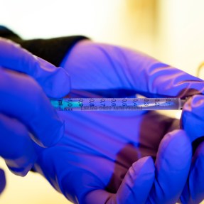 A person filling a syringe.