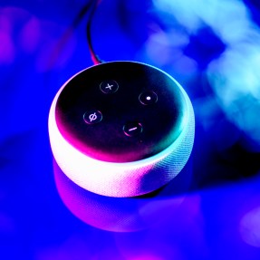 An Amazon Alexa sitting on a purple surface.