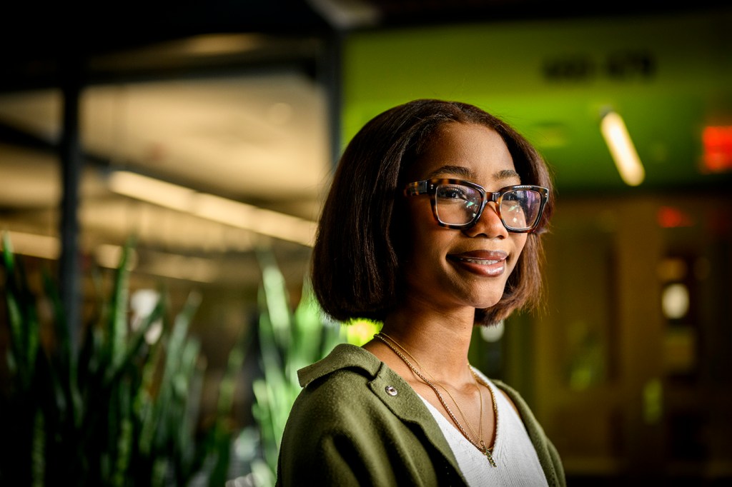 Portrait of TaKaya McFarland wearing glasses, a white shirt and a green sweater.