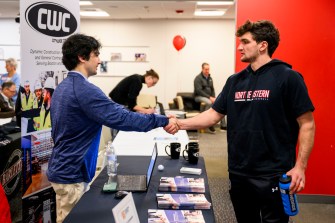 Two people shaking hands at the athletics co-op fair.