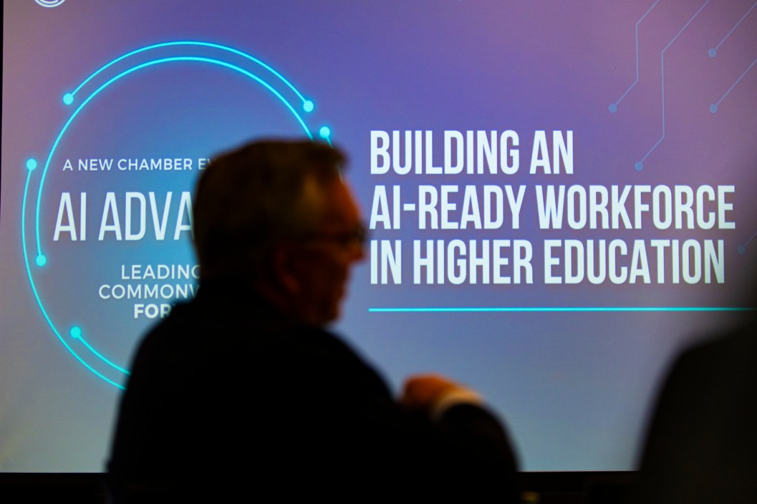 The silhouette of a person sitting in front of a screen that says 'Building an AI-Ready Workforce in Higher Education'.