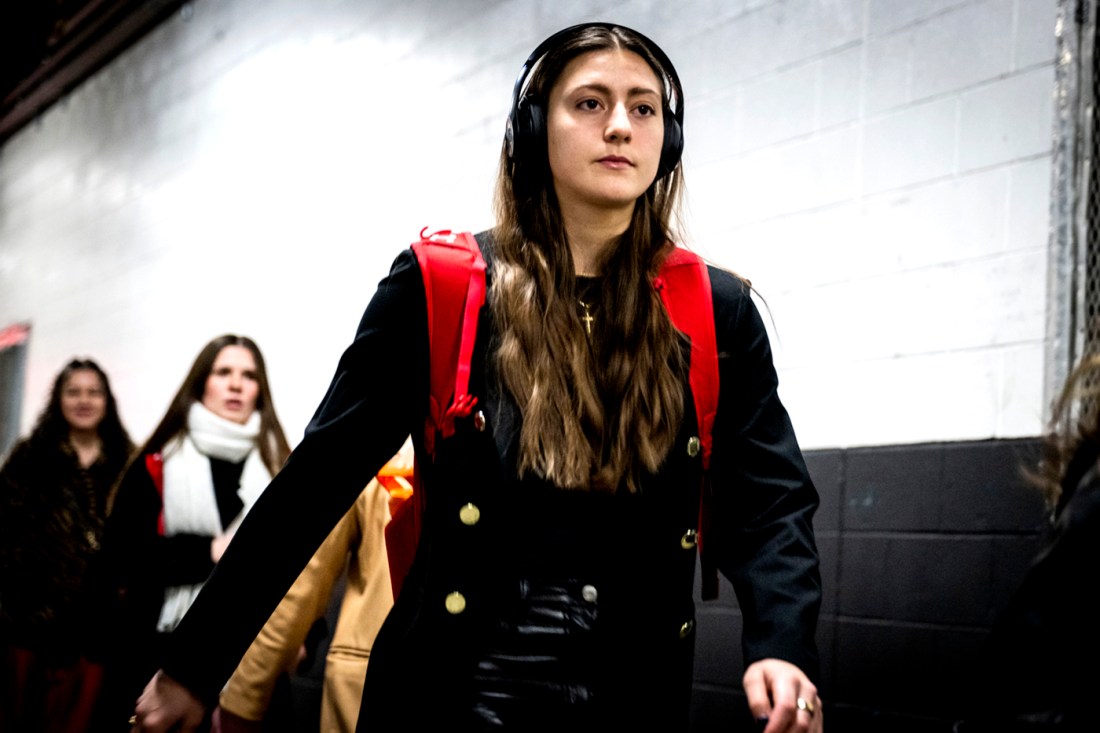 A women's hockey player walking into to TD Garden wearing over the ear headphones.